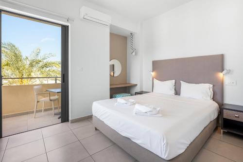 a bedroom with a large white bed and a balcony at Amaryllis in Platanias
