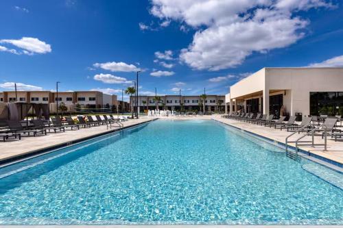 a swimming pool with chairs and a building at Elegant Home w 3 En Suites & Breathtaking View in Orlando