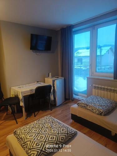 a room with two beds and a table and a window at Noclegi Spoko in Mąchocice