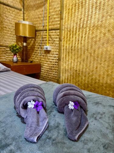 a pair of purple socks with flowers on a bed at Bunga Hut Koh Lanta in Ko Lanta