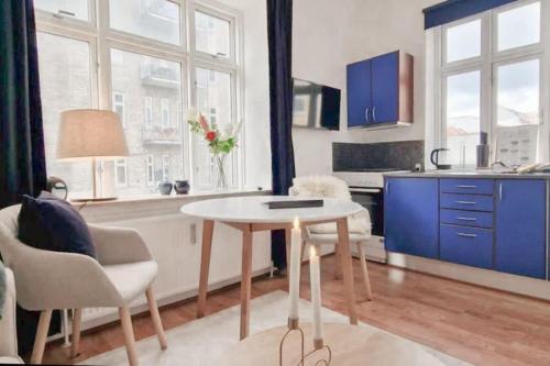 a kitchen with a table and chairs and blue cabinets at Central 1BR Studio - Walk Everywhere in Aarhus in Aarhus