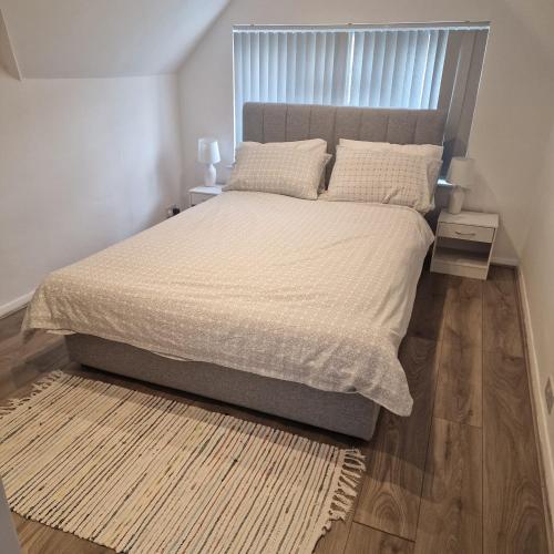 a bedroom with a large bed with white sheets and a rug at Clover Crest - 3-Bedroom House in Bourton on the Water