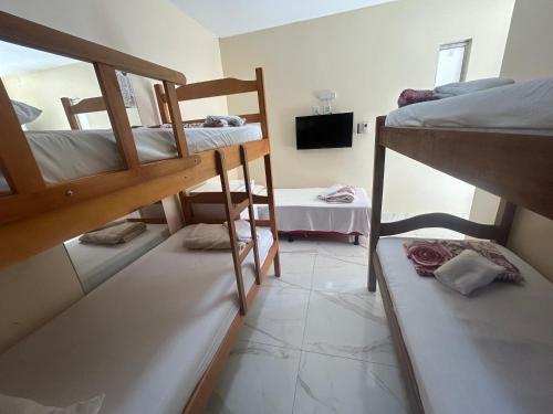 a room with two bunk beds and a television at Village enseada do castelo-com carregador de carros eletricos in Praia do Forte