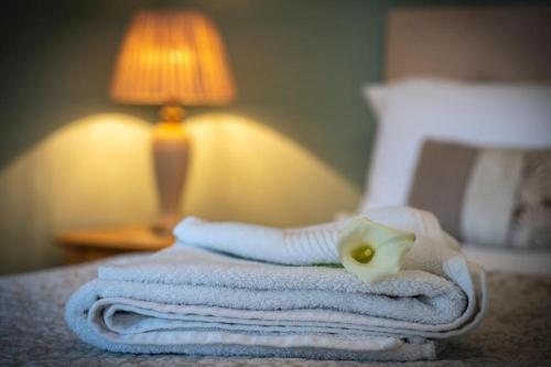 a pile of towels on a bed with a lamp at Keons Town House in Longford