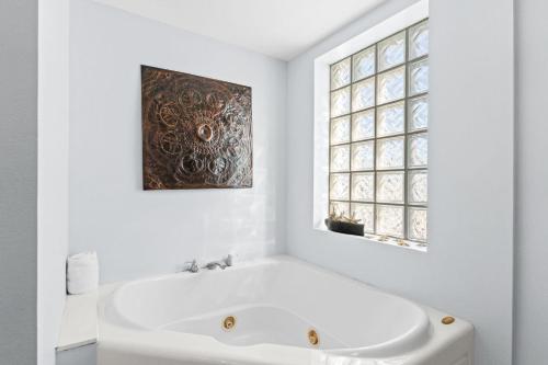 a white bathroom with a tub and a window at Dune Pointe 402 - Shells, Surf & Sea Turtles in Fort Walton Beach