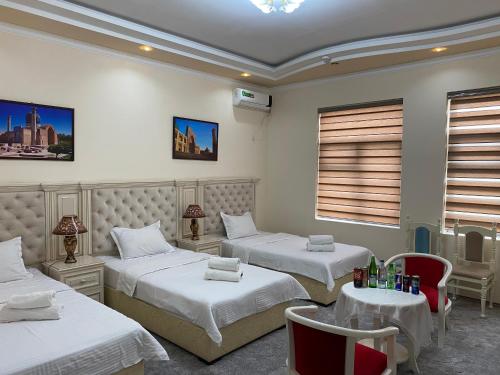 a hotel room with two beds and a table and chairs at Amina in Samarkand