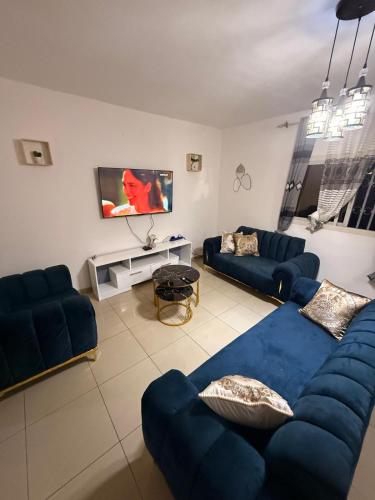 a living room with blue couches and a tv at Appartement Dan'L Ngousso in Yaoundé