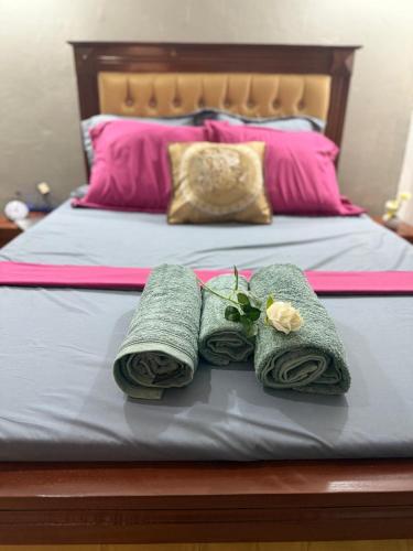 a bed with three towels and a flower on it at Appartement Dan'L Ngousso in Yaoundé