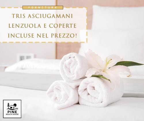 Ein paar Handtücher auf einem Tisch mit einer Blume in der Unterkunft Pine Beach House - Villaggio Turistico con Piscina e Animazione in Campofelice di Roccella