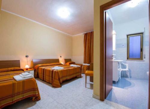 a hotel room with two beds and a bathroom at Fruit Village Capo Rizzuto S Antonio in Capo Rizzuto