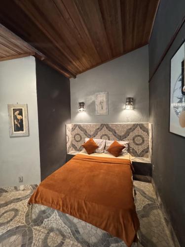 a bedroom with a large bed with orange sheets and pillows at Pousada O Povorello - a 1 minuto a pé da Praia Grande da Baía do Sol in Mosqueiro