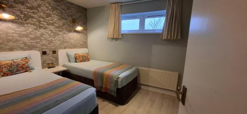 a small room with two beds and a window at Guest Lodge by The Promenade in Penzance
