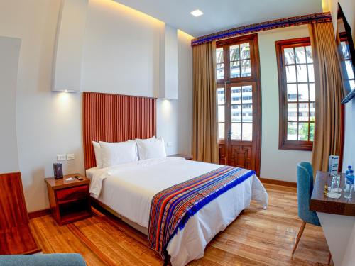 a hotel room with a bed and two windows at Hotel Boutique Circasiana Palace in Quito