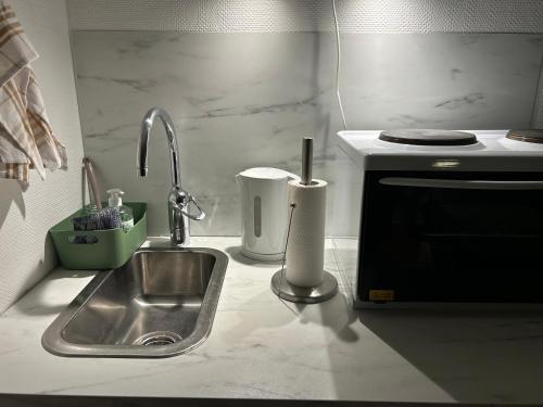 a kitchen counter with a sink and a microwave at Sentralt og koselig in Kristiansand