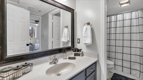 a white bathroom with a sink and a mirror at The Fox Hunt - A Ground Floor Condo in Southern Pines
