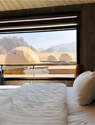 a bedroom with a bed and a view of the desert at Moonlight Luxury Bubble Camp & Jeep Tours in Wadi Rum