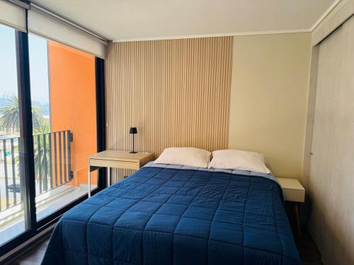a bedroom with a blue bed and a large window at Studio Frente Al Muelle Barón in Valparaíso