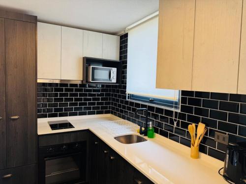 a kitchen with a sink and a microwave at Studio Frente Al Muelle Barón in Valparaíso