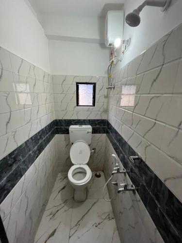 a bathroom with a white toilet and a window at Top Comfort in Kolkata