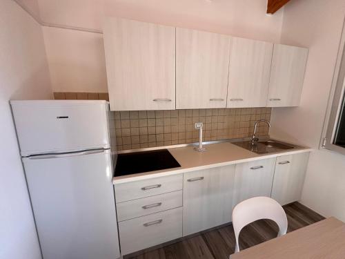 a kitchen with white cabinets and a white refrigerator at Risa Apulia in Torre Lapillo