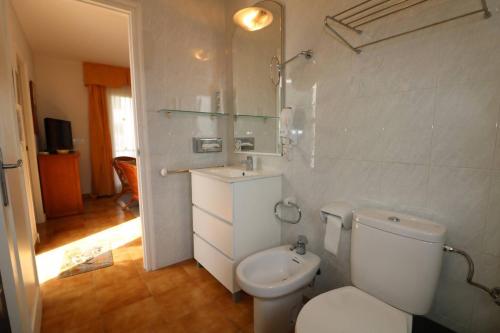 a white bathroom with a toilet and a sink at Apartamento Complejo Pinimar in Port d'Addaia
