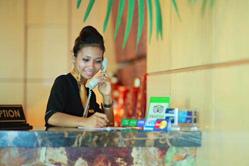 a woman talking on a cell phone at a counter at Rocky Plaza Hotel Padang in Padang