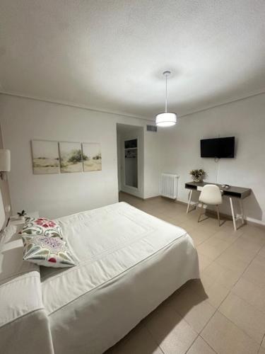 a white bedroom with a bed and a desk at Hotel Castillo de Montemayor in Montemayor