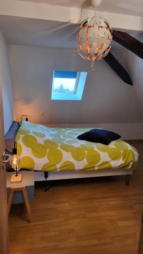 a bedroom with a yellow and white bed and a chandelier at Le Clocher, nice warm and comfortable nest in Sierentz