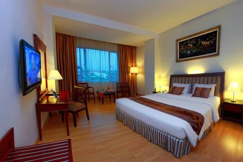 a hotel room with a large bed and a television at Rocky Plaza Hotel Padang in Padang