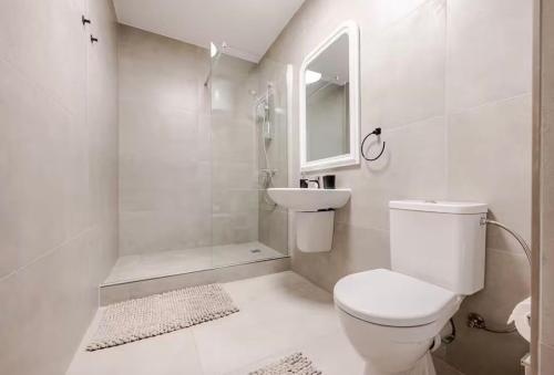 a white bathroom with a toilet and a sink at Gzira Getaway in Il-Gżira