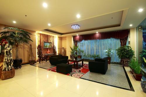 a living room with chairs and tables and plants at Rocky Plaza Hotel Padang in Padang