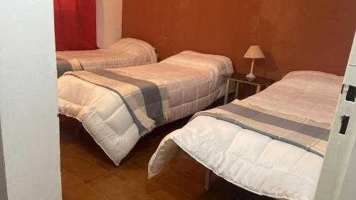 a room with three beds and a table with a lamp at Hotel Corona del inca in Vinchina