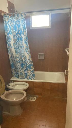 a bathroom with a toilet and a shower curtain at Hotel Corona del inca in Vinchina