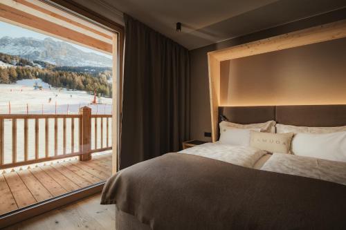 a bedroom with a bed and a large window at Hotel La Müda in Badia