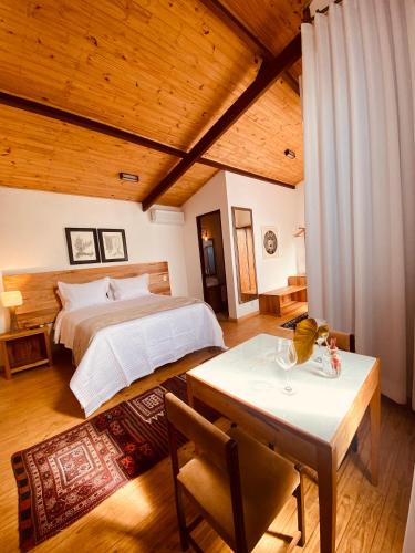 a bedroom with a large bed and a table at Suítes Ad`vinho in Lavras Novas