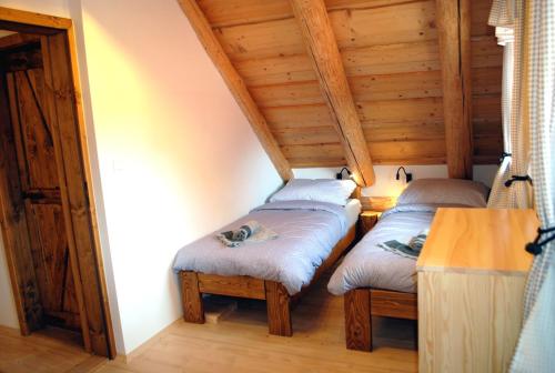 two twin beds in a room with wooden ceilings at Penzión NOVA in Spišská Stará Ves
