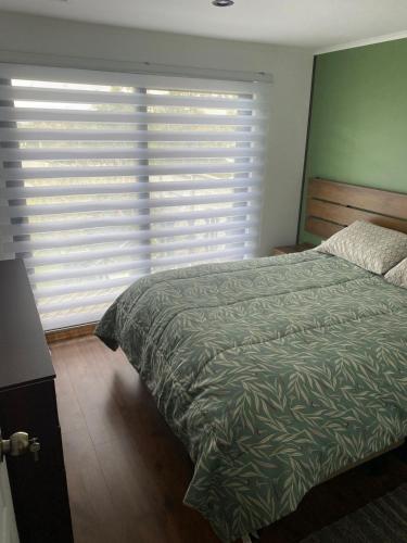 a bedroom with a bed and a large window at Los Ciruelos Cabin in Calbuco