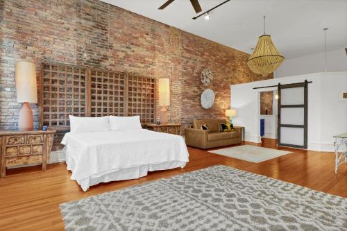 a bedroom with a white bed and a brick wall at Luxe 220 Suite 4 in Wilmington