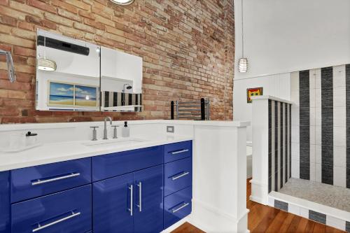 a bathroom with blue cabinets and a brick wall at Luxe 220 Suite 4 in Wilmington