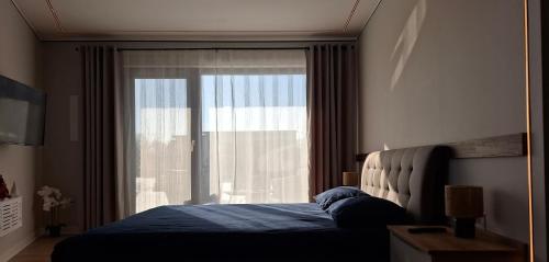 ein Schlafzimmer mit einem Bett und einem großen Fenster in der Unterkunft Respiro Villas in Târgu Neamţ