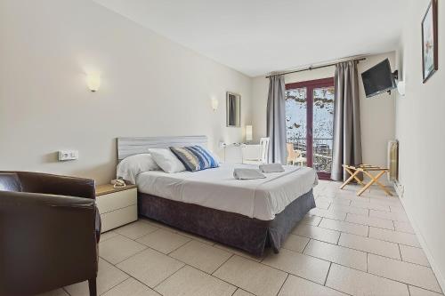 a bedroom with a large bed and a chair at Hotel Xalet Besolí in Arinsal