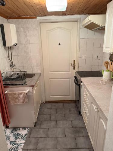 a kitchen with a white door and a tile floor at Romantický vejminek pod horami in Kounov