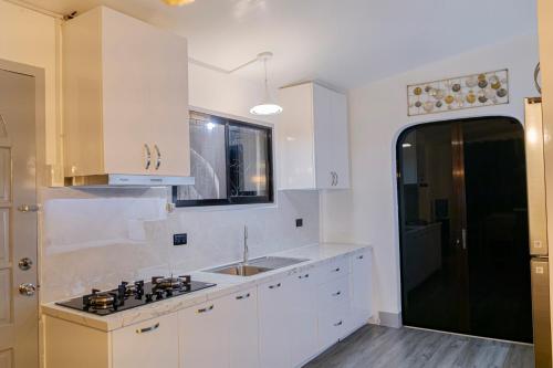 a kitchen with white cabinets and a sink and a window at Casa Mutya in Dauis