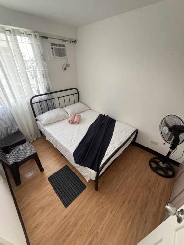 a small bedroom with a bed and a fan at Arezzo Place Davao in Davao City