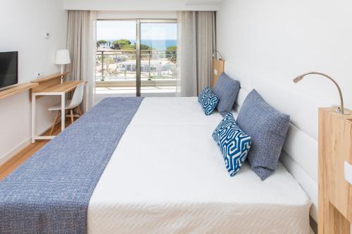 a bedroom with a large bed with blue pillows at Alfagar Prestige in Albufeira
