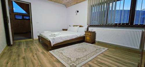 a bedroom with a bed and a large window at Casa LUMINITA in Cîrlibaba