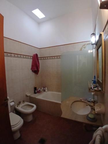 a bathroom with a toilet and a tub and a sink at Casa Corna in Río Cuarto
