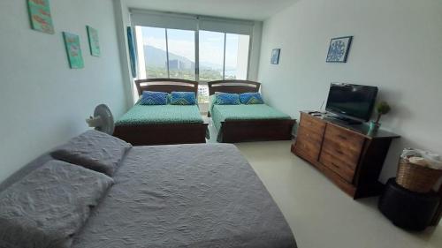 a bedroom with two beds and a tv in it at Apartamento Frente al Mar in Santa Marta