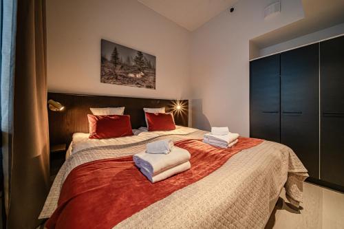 a bedroom with a large bed with red pillows at Le Chalet Lingonberry D3 Ski-in Ski-out, Hot Tub by Aavalevi in Levi