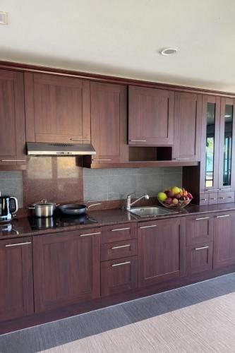 a kitchen with wooden cabinets and a bowl of fruit at Rosdao Beachfront Villa in Ban Khlong Son